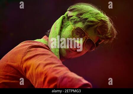 A HAPPY YOUNG MAN CHEERFULLY BENDING AND POSING IN FRONT OF CAMERA DURING HOLI Stock Photo