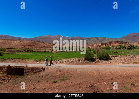 Telouet, Morocco - April 14, 2016: Two man walking along a road near the village of Telouet, in the Atlas Mountains region of Morocco. Stock Photo