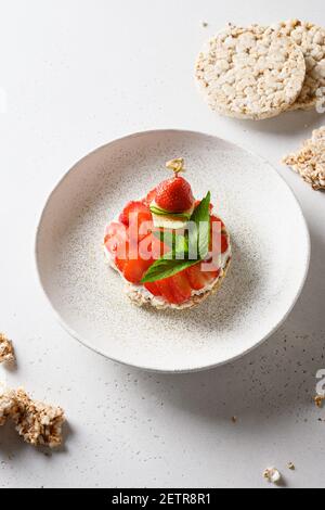 Rice vegan crispbread with toppings of strawberries on white table. Close up. Vertical format. Stock Photo