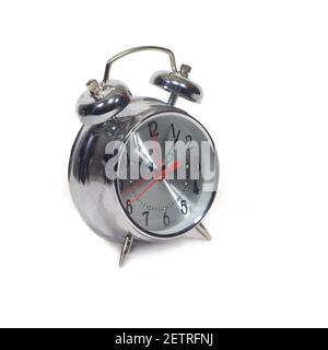 Table alarm clock in silver stainless steel body with a round shape of the dial, showing five minutes past ten isolated on a white background side vie Stock Photo