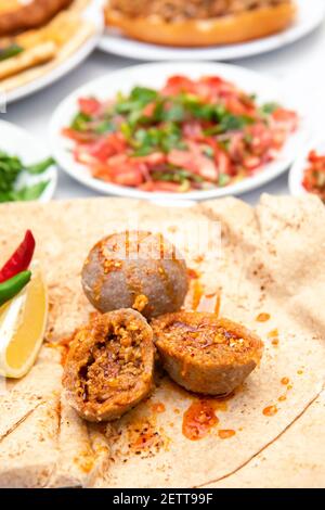 Kibbeh also known icli kofte - traditional Arabian meatballs, minced meat and bulgur or rice wheat fried snack with mint, in white plate on isolated w Stock Photo