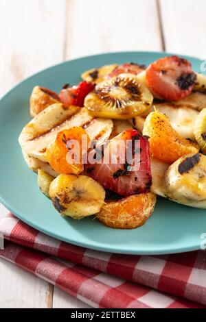 GRILLED FRUIT on a blue plate and white wooden background Stock Photo