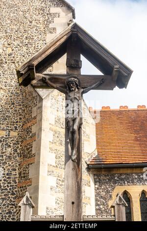 A carving of Jesus Christ being crucified on a wooden cross stands outside a church. Stock Photo