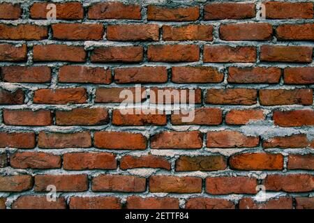 Old brick wall with cracks and scratches. Horizontal wide brickwall background. Distressed wall with broken bricks texture. Vintage house facade. Stock Photo