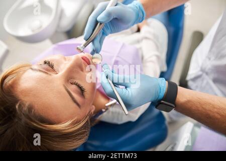 Dental practitioner keeping mirror and drill for mouth Stock Photo