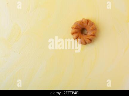 Top view of a glazed bite size cruller on a yellow painted background illuminated with natural light. Stock Photo