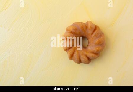 Top view of a glazed bite size cruller on a yellow painted background. Stock Photo