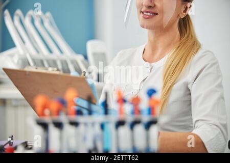 Joyful lady taking notes while holding clipboard Stock Photo