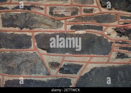 Close view of an old slate stone wall with raised masonry seams. Stock Photo