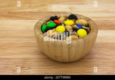 Sweet and salty trail mix in a wood bowl isolated on a countertop side view. Stock Photo