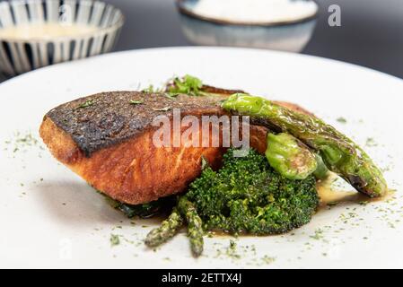 Thick piece of salmon steak over a bed of sauteed vegetables with rice and bowl of miso soup. Stock Photo