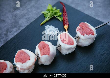 Raw and fresh beef meat steaks on the black background. Skewers of fresh and raw shish kebab or barbecued shashlik meat. Stock Photo