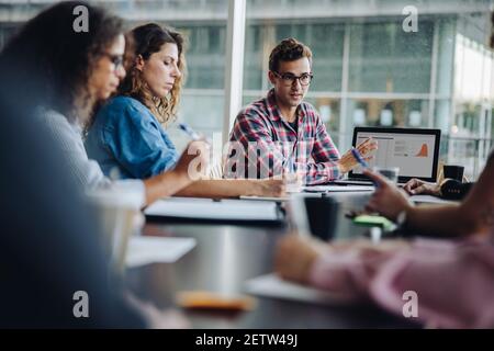 businessman sharing his ideas with laptop to colleagues. business people meeting in office and discussing over new project. Stock Photo
