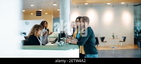 People standing in the hall of a municipal office and talking with the administrators. Municipality office reception with people being assisted by the Stock Photo