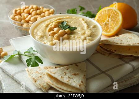 Concept of tasty eat with bowl of hummus on gray background Stock Photo
