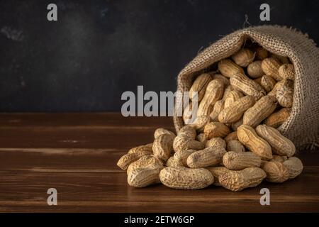 Peanut in sack bag on wooden background. Food background. Stock Photo
