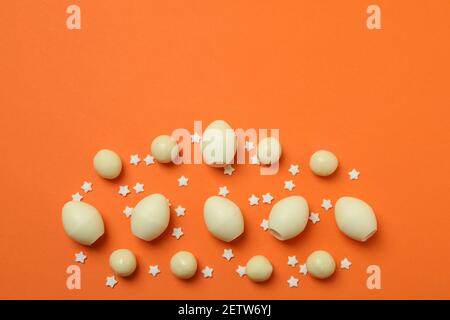 Easter chocolate eggs and sprinkles on orange background Stock Photo