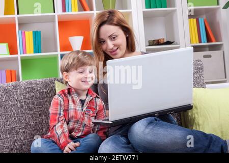 Happy mother and son using computer on the couch Stock Photo
