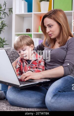 Scary mother and happy son using computer Stock Photo