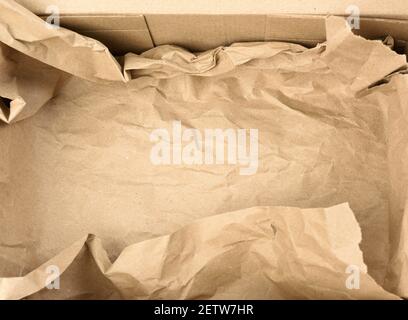 open empty rectangular brown cardboard box for transportation and packaging of goods, top view. At the bottom is a piece of brown paper Stock Photo