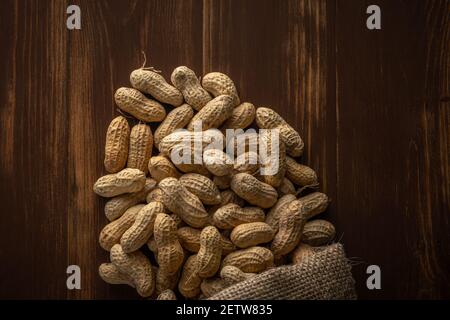 Peanut in sack bag on wooden background. Food background. Stock Photo
