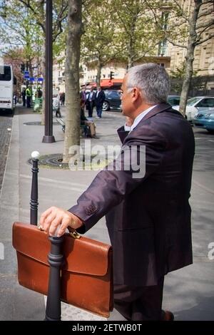 A business man in a suit stands with a briefcase in his hands Stock Photo