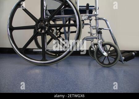 Close crop of black and chrome medical wheelchair alone waiting for a patient in a clean and sterile hospital facility hallway Stock Photo