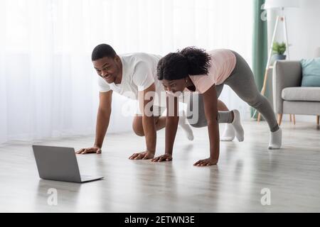 Sporty african american couple having online fitness class, using laptop Stock Photo