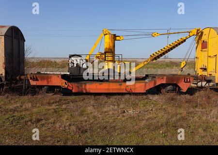 Old yellow cargo crane wagon on abandoned train tracks in the field Stock Photo