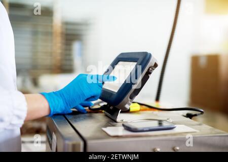 Close up view of a touchscreen control panel of big machine used by a worker in a sterile cloth. Stock Photo