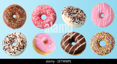 Different fresh donuts on blue background. Minimal food concept. Stock Photo