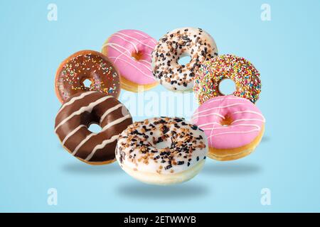 Different fresh donuts on blue background. Minimal food concept. Stock Photo