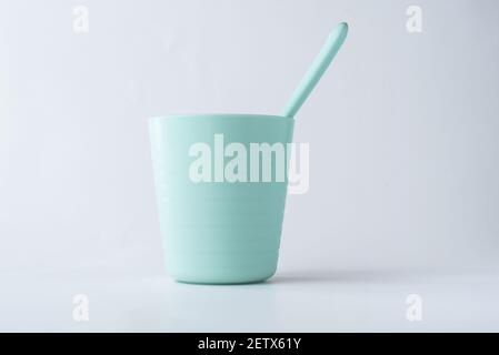 Plastic cup and a spoon isolated on white background, Kids green colorful plastic cutlery Stock Photo