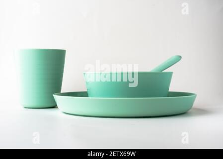 Plastic cup, plate and a spoon isolated on white background, Kids green colorful plastic cutlery Stock Photo