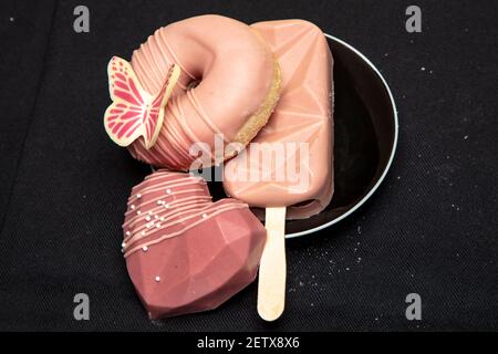 set of sweets lies on a black plate, isolated on a black background Stock Photo