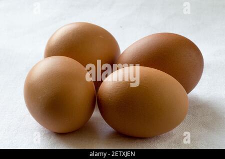 Four eggs on a white table cloth Stock Photo