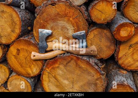 Two axes cross on front of felled tree trunks, Lumberjack Heritage Festival, Stack of Wood Stumps, Wooden background. Copy Space. Stock Photo