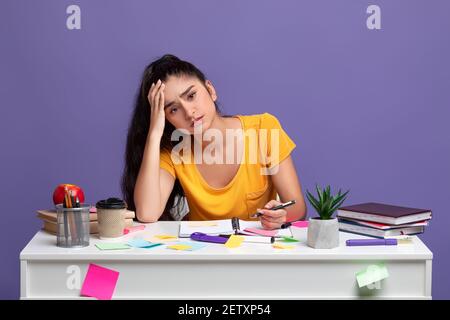 Tired indian woman sitting at desk and reading book Stock Photo - Alamy
