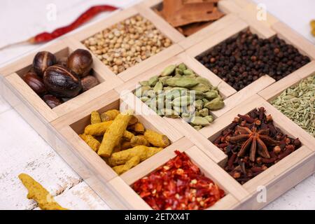 Indian spices for Indian cooking Masala hot spicy curry whole spices turmeric, cardamom, black pepper in wooden spoon curry leaves paprika in Indian Stock Photo