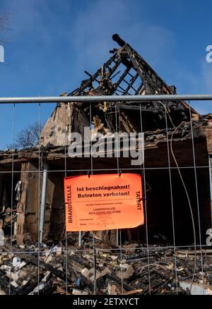 Nortorf, Germany. 02nd Mar, 2021. A sign reading 'Is confiscated. No trespassing' by the state police hangs on a fence in front of the remains of an end-terrace house that was almost completely destroyed in an explosion. One day after the explosion in the house in Nortorf (Rendsburg-Eckernföde district), a 54-year-old female resident is still missing. Credit: Axel Heimken/dpa/Alamy Live News Stock Photo