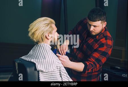 Men's haircut at the barber scissors. Man with beard and blond hair in vintage barbershop. Stock Photo