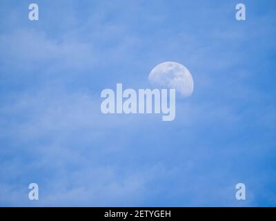 Cloudy blue sky with an illuminated moon during the hours of daylight. Stock Photo