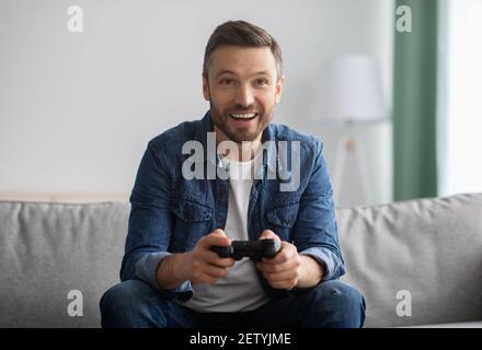 Emotional middle-aged man playing video games at home Stock Photo