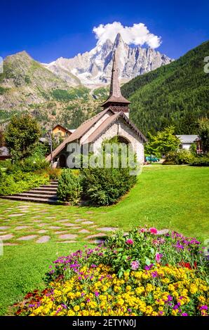 Chamonix, Mont Blanc. Old stone Les Praz Chapel in Chamonix touristic valley, Aiguille du Midi mountain in France. Stock Photo