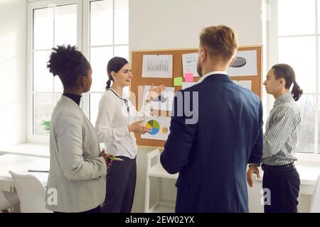 Office workers of different nationalities discuss and analyze graphs and charts together. Stock Photo