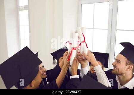 Smiling university students in traditional black hats celebrating successful graduation Stock Photo