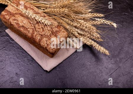Loaf of whole grain bread and shocks of wheat. Rustic sourdough bread Stock Photo