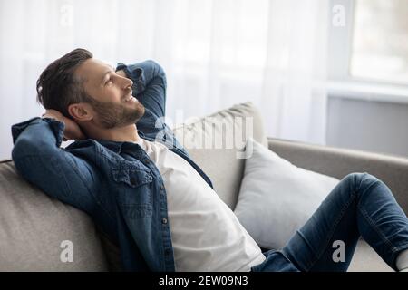 Closeup of carefree bearded man relaxing on couch at home Stock Photo