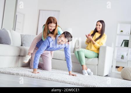 Photo portrait of daughter playing with dad sitting on his back near mom clapping hands at home holidays Stock Photo