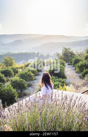 View from a little hillside village in Cyprus, overlooking hills with morning mist in the distance. Woman  looking overlooking in the distance. Stock Photo